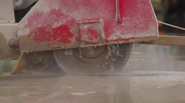 Endüstriyel elmas zemin testeresiyle beton kesmek. İnşaat alanında ıslak beton kesen endüstriyel beton testeresinin yakın çekimi. Elmas bıçak suyla soğutulmuş..