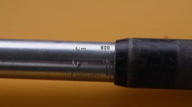 Bir işçi tork anahtarı kullanır. Mavi tulumlu bir tamircinin, ağır sarı çelik bir yapının sürgüsünü sıkılaştırmak için profesyonel kiriş tipi tork anahtarı kullanması..