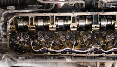 Bir araba motorunun şaft ve vana tren bileşenleri. Mekanik inceleme ve belgelendirme metal motor bileşenleri. Profesyonel oto tamiratı sırasında atölyedeki bir çalışma tezgahında çalışan bir motor mekanizması.