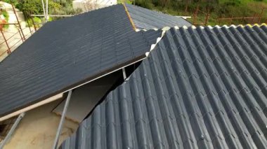 Karmaşık bir binaya antrasit metal çatı kiremitleri yerleştirilmiş. Yüksek açılı İHA görüntüleri, inşaatın inşaat alanındaki ilerlemesini gösteriyor. Yenilikçi yalıtım malzemeleri.