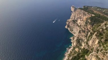 Capri sahil şeridi ve Punta Carena deniz fenerinin panoramik görüntüsü. Bu insansız hava aracı Capri 'nin uçurumlarını, derin mavi suları ve tarihi deniz fenerini gösteriyor..