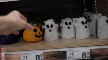 Perakende satış rafındaki küçük balkabakları ve beyaz hayalet heykelcikleri içeren Cadılar Bayramı süslemeleri