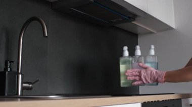 A woman places cleaning products on the kitchen countertop. The concept of maintaining order and cleanliness at home