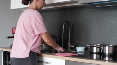 Female cleaning tableware at sink, water running from faucet, kitchen utensils and cookware in background. Concept of responsibility, housework and cleanliness