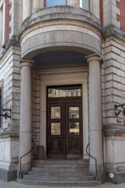 Riga, Letonya - 20 Temmuz 2025: Riga, Letonya 'da Pils iela caddesindeki tarihi bina girişi, neoklasik sütunlar ve ahşap kapılar