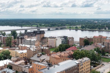 Riga, Letonya - 20 Temmuz 2025: Riga şehri panoramik manzarası yüksek perspektiften şehrin çatıları ve Daugava nehri ufuk çizgisi üzerinden