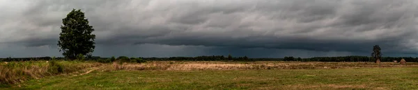 Dramatic view of a shelf cloud over a field, horizontal cloud fo