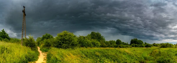 Dramatic view of a shelf cloud over a field, horizontal cloud formation, panorama view.