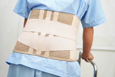 Bel ağrısı çeken Asyalı bir kadın. Hastanede yürüteç kullanıyor..