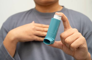 Astım ve kronik obstrüktif akciğer hastalığı COPD, Asyalı genç adam ölçülü doz solunum cihazı kullanıyor..