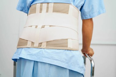 Bel ağrısı çeken Asyalı bir kadın. Hastanede yürüteç kullanıyor..