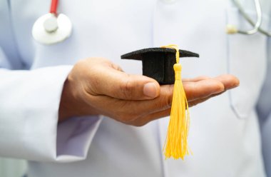 Hastanede mezun şapkası tutan Asyalı kadın doktor. Tıp eğitimi almış..