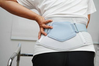 Bel ağrısı çeken Asyalı bir kadın. Hastanede yürüteç kullanıyor..