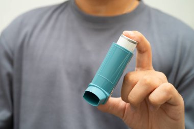 Astım ve kronik obstrüktif akciğer hastalığı COPD, Asyalı genç adam ölçülü doz solunum cihazı kullanıyor..
