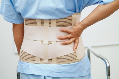 Bel ağrısı çeken Asyalı bir kadın. Hastanede yürüteç kullanıyor..