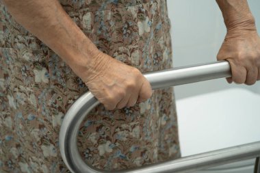 Asyalı yaşlı kadın hasta tuvalette tuvalet desteği kullanıyor..