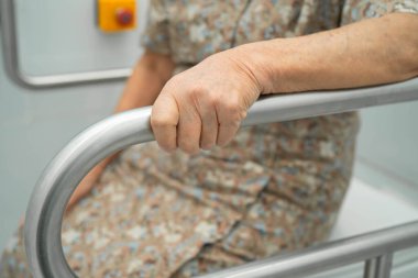 Asyalı yaşlı kadın hasta tuvalette tuvalet desteği kullanıyor..