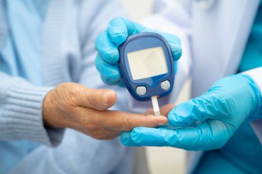 Diyabet tedavisinde kan şekeri seviyesini kontrol etmek için dijital glikoz ölçer kullanan Asyalı doktor.