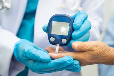 Diyabet tedavisinde kan şekeri seviyesini kontrol etmek için dijital glikoz ölçer kullanan Asyalı doktor.