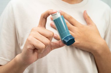 Astım ve kronik obstrüktif akciğer hastalığı KOAH, Asyalı genç ölçülü doz solunum cihazı kullanıyor..