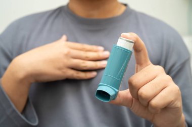 Astım ve kronik obstrüktif akciğer hastalığı COPD, Asyalı genç adam ölçülü doz solunum cihazı kullanıyor..