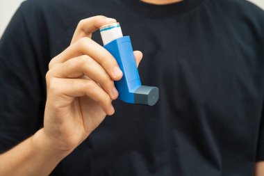 Astım ve kronik obstrüktif akciğer hastalığı KOAH, Asyalı genç ölçülü doz solunum cihazı kullanıyor..