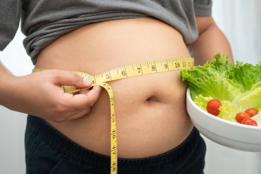 Koca göbekli, şişman, kilolu ve sağlıklı yiyecekleri olan Asyalı bir kadın..