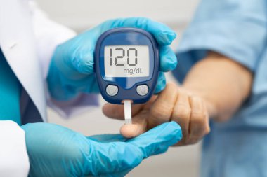 Diyabet tedavisinde kan şekeri seviyesini kontrol etmek için dijital glikoz ölçer kullanan Asyalı doktor.