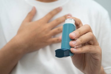 Astım ve kronik obstrüktif akciğer hastalığı KOAH, Asyalı genç ölçülü doz solunum cihazı kullanıyor..