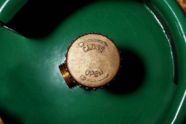 Yeşil sıvılaştırılmış bir gaz silindirinde kapalı kapaklı vananın yakın plan görüntüsü..