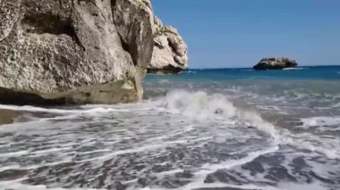 Kıbrıs 'taki Afrodit Sahili' nde büyük bir kıyı kayası ve kumlu sahile vuran Akdeniz dalgalarının yakın çekimi romantik, mitolojik, rahatlatıcı ve yaz tatili kavramları için mükemmeldir..
