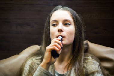 Buharlı genç. İçeride elektronik sigara içen, beyaz tenli, beyaz, genç bir kız. Çok kötü bir alışkanlık. Vestiyer etkinliği.