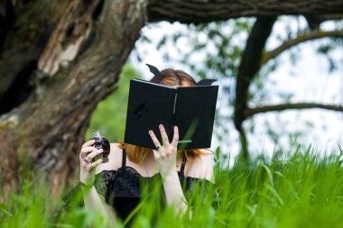 Siyah elbiseli genç ve güzel cadı bir yaz günü yeşil bir ormanda bir tören düzenliyor. Modern cadılık..
