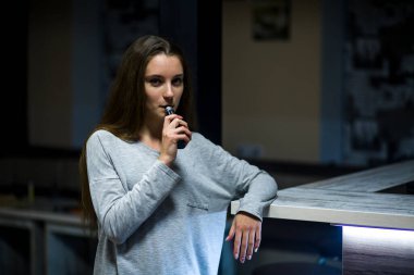 Buharlı genç. İçeride elektronik sigara içen, beyaz tenli, beyaz, genç bir kız. Çok kötü bir alışkanlık. Vestiyer etkinliği.