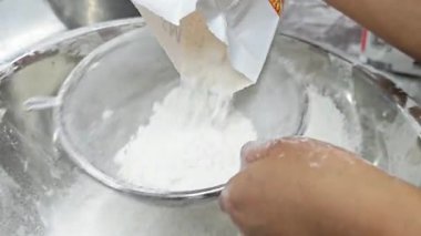 Un elek ile eleme yakın çekim, fırın tarzı bir mutfakta pişirme hazırlama işlemi yakalamak.