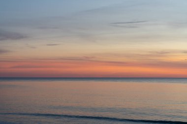 Renkli gökyüzü ve küçük dalgalarla okyanusun üzerinde güzel bir gün batımı