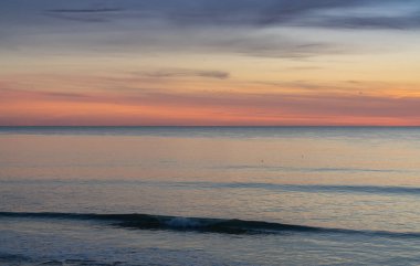 Renkli gökyüzü ve küçük dalgalarla okyanusun üzerinde güzel bir gün batımı