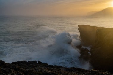 Büyük bir fırtınanın dalgalanan okyanus dalgalarının kıyıya çarpması ve gün doğumunda kayalıklara çarpması.