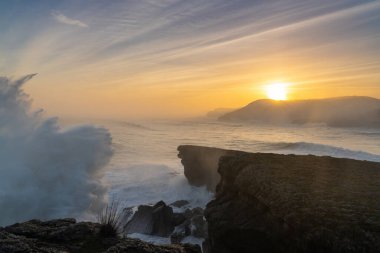 Büyük bir fırtınanın dalgalanan okyanus dalgalarının kıyıya çarpması ve gün doğumunda kayalıklara çarpması.