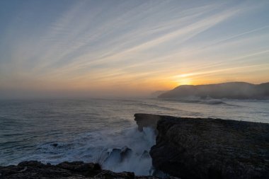 Büyük bir fırtınanın dalgalanan okyanus dalgalarının kıyıya çarpması ve gün doğumunda kayalıklara çarpması.