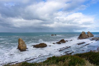 Kıyıya vuran fırtınalı dalgalarla kayalık ve vahşi bir sahil.