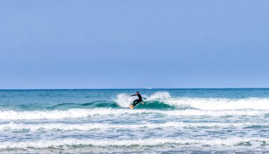 Rodiles, Asturias / İspanya - 6 Kasım 2020: İspanya 'nın kuzeyinde Asturias' ta muhteşem dalgalarda sörf yapan dalgıç kıyafetli adam