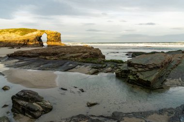 Güneşin doğuşuyla güzel bir kumsal ve kayalık uçurumlar.
