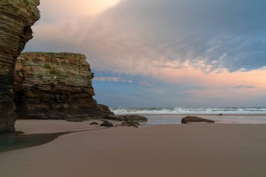 Güneşin doğuşuyla güzel bir kumsal ve kayalık uçurumlar.