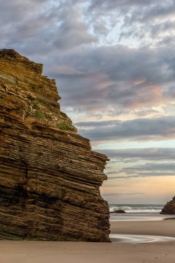 Güneşin altında güzel bir kumsal ve kayalık kayalıklar.