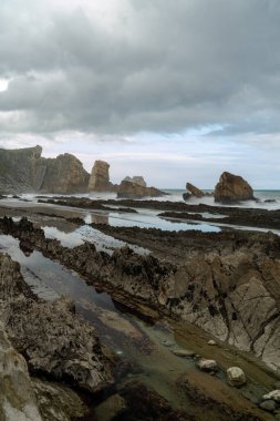 Kıyıya vuran fırtınalı dalgalarla kayalık ve vahşi bir sahil.