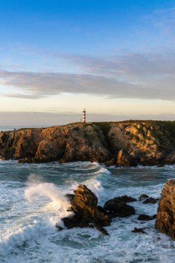 Gün batımında engebeli Alentejo kıyı şeridi ve Porto Covo deniz feneri manzarası