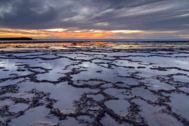 Okyanusun üzerinde güzel bir gün batımı kayalık plajlar ve ön planda gelgit havuzları.