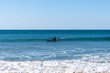 Arrifana, Portekiz - 26 Aralık 2020: Turkuaz renkli okyanus suyunda dalgaları yakalayan adam