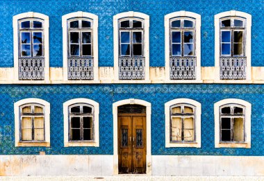 Kırık camlı ve ahşap kapılı Azulejo fayanslarıyla kaplı bir evin ön cephesi.